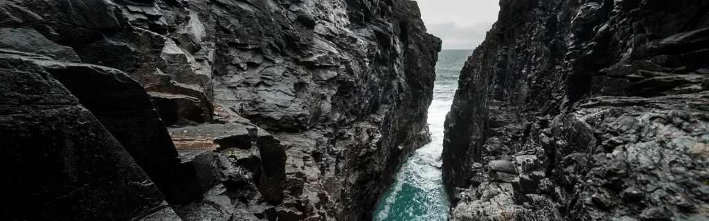 Hells Hole, a subterranean cavern into which the Atlantic tide explodes with a tremendous force, at Malin Head, Donegal, Ireland.