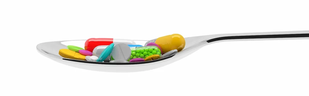 Several pills and medicines in a spoon